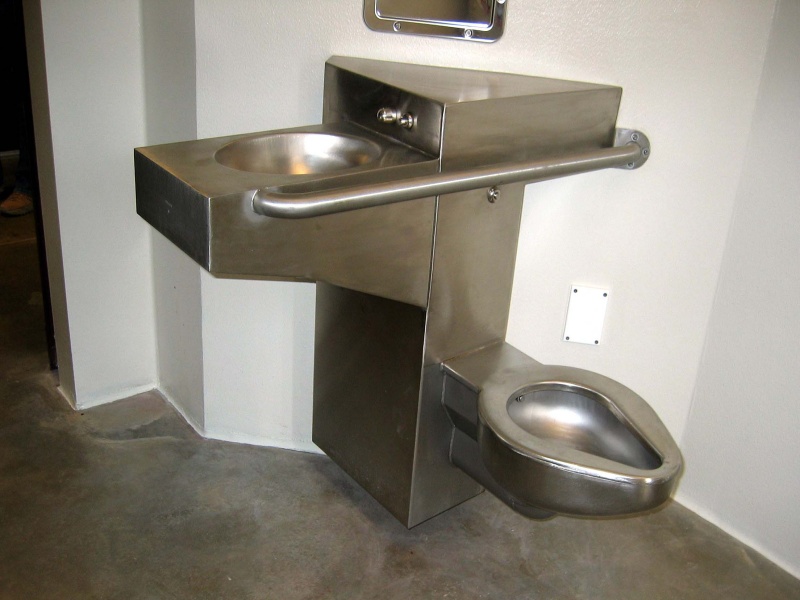 Camp 5 cell featuring an overhanging sink to accommodate detainees with disabilities who can use a wheelchair and a grab bar on the commode