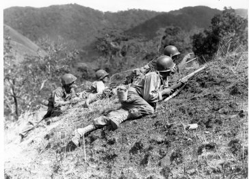 A squad leader of the 25th Infantry Division points out a suspected enemy position near Baugio, Luzon on 23 March 1945.