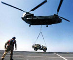 An RAF Chinook flying vehicles ashore from HMS OCEAN
