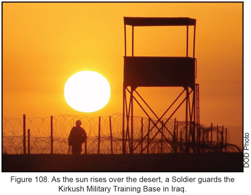 Figure 108. As the sun rises over the desert, a Soldier guards the Kirkush Military Training Base in Iraq.