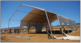Photo of Seabees from Amphibious Construction Battalion 1 erect the metal frame of a tension fabric structure