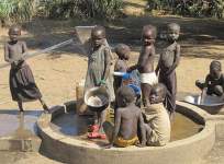 Photo showing children drawing water from a local pump