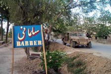 An Afghan man looks at a sign while another talks with a coalition soldier in a Humvee at Bagram Air Base in Afghanistan