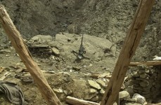 A high caliber weapon used by Taliban and al-Qaeda forces that presumably occupied the bombed out building seen in the foreground, stands guard over the valley below