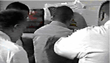 Image 2:  Officers face detainee towards t-shirt with flag.