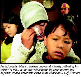 An Indonesian Muslim woman grieves at a family gathering for victims of the J.W. Marriott Hotel bombing, while holding her nephew, whose father was killed in the attack, 5 August 2003. [AFP photo]