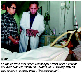 Philippine President Gloria Macapagal-Arroyo visits a patient at Davao Medical Center on 5 March 2003, the day after he was injured in a bomb blast at the local airport. [AFP photo]