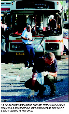 An Israeli investigator collects evidence after a suicide attack blew apart  a passenger bus just before morning rush hour in east Jerusalem, 18 May 2003. 