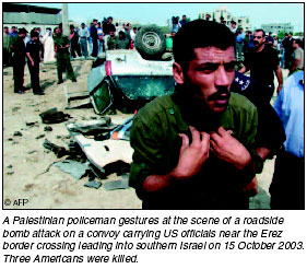 A Palestinian policeman gestures at the scene of a roadside bomb attack on a convoy carrying US officials near the Erez border crossing leading into southern Israel on 15 October 2003.
