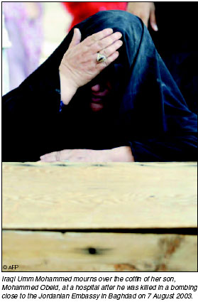Iraqi Umm Mohammed mourns over the coffin of her son, Mohammed Obeid, at a hospital after he was killed in a bombing close to the Jordanian Embassy in Baghdad, destroyed on 19 Augusrt 2003. [AFP photo