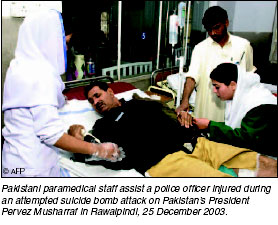 Pakistani paramedical staff assist a police officer injured during an attempted suicide bomb attack on Pakistanis President Perves Musharraf in Rawalpindi, 25 December 2003. [AFP photo]