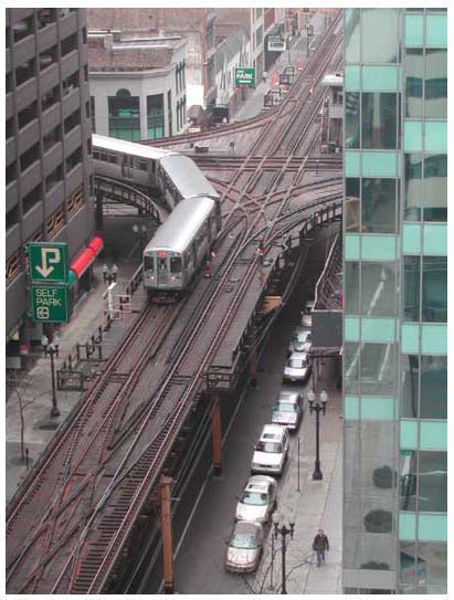 Photo showing an elevated train traveling along tracks in an urban neighborhood