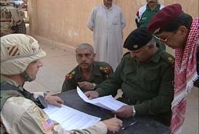  Iraqi Maj. Gen. Muhammed Thumayla, commander, Iraq's Western District, reviews the articles of capitulation while Col. Curtis D. Potts, commander, 4th Brigade, explains the surrender to him through an interpreter. (Photo by Spc. Jacob Boyer)